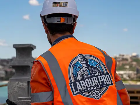 Labour Pro Group traffic controller in an orange hi-vis vest with radio overlooking a Sydney work site